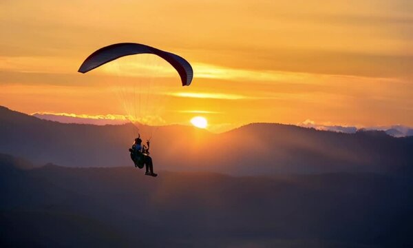 Sunset Paragliding: A silhouette of a paraglider soaring through the sky, bathed in the warm hues of a breathtaking sunset.