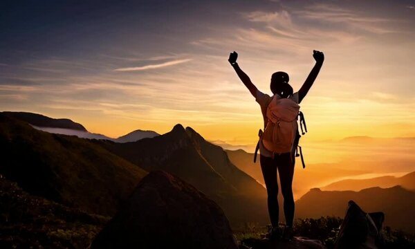 Summit Success: A silhouette of a triumphant hiker with arms raised in victory, standing atop a mountain peak as the sun sets, a powerful symbol of perseverance and achievement. 