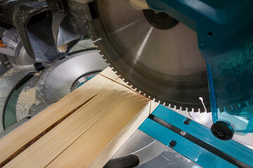 A miter saw for sawing wood.Sawing wooden bars on the machine.