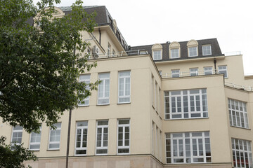 A large architectural building featuring numerous windows, complemented by a beautiful tree strategically located in front of it