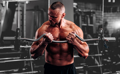 Handsome young fit muscular man training in the gym gaining weight pumping up muscles....