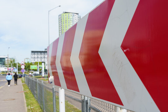 Bright red directional indicators guiding pedestrians through an urban area