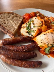 Shakshuka breakfast with sausage links and toast