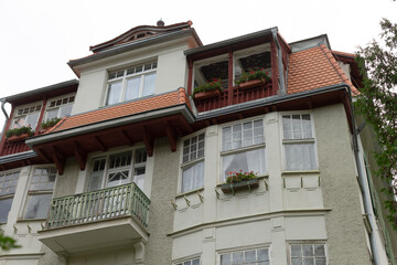 There is a very large white house that features a striking red roof and multiple beautiful balconies that enhance its charm and appeal