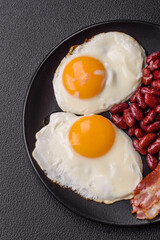 English breakfast with fried eggs, bacon, beans, tomatoes, spices and herbs