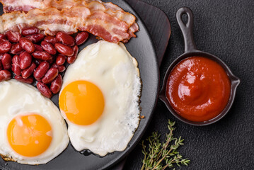 English breakfast with fried eggs, bacon, beans, tomatoes, spices and herbs