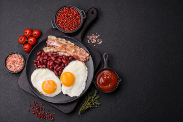 English breakfast with fried eggs, bacon, beans, tomatoes, spices and herbs