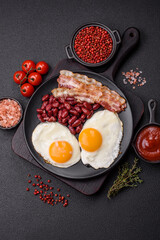 English breakfast with fried eggs, bacon, beans, tomatoes, spices and herbs