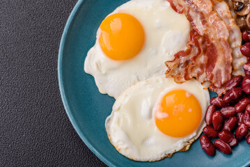 English breakfast with fried eggs, bacon, beans, tomatoes, spices and herbs