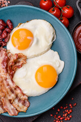 English breakfast with fried eggs, bacon, beans, tomatoes, spices and herbs