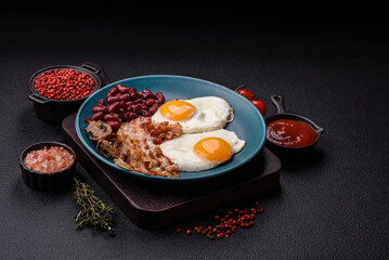 English breakfast with fried eggs, bacon, beans, tomatoes, spices and herbs