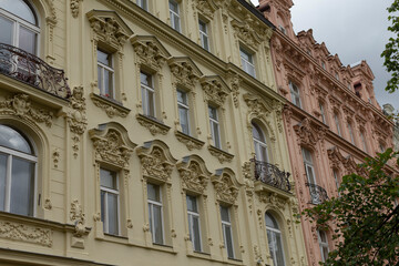 In a row, there are several buildings showcasing numerous windows and balconies, all observed on a cloudy day in the city