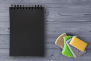 Cleaning service template. Black notebook page and kitchen sponges. Blank notepad with empty space for copyspace, advertising, text. Home Cleaning Instructions and Tips.