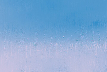 Through the glass fogged with water droplets, the blue sky and pink dawn are visible