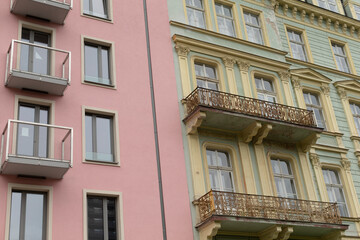 Fototapeta premium A lovely pink building featuring charming balconies is located right next to a vibrant green building which also has its own balconies