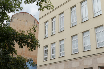 There is a large building with numerous windows, prominently displaying its architecture, and in front of this building, there is a tree