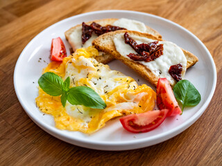 Continental breakfast - scrambled eggs, bruschetta and fresh vegetables on wooden table