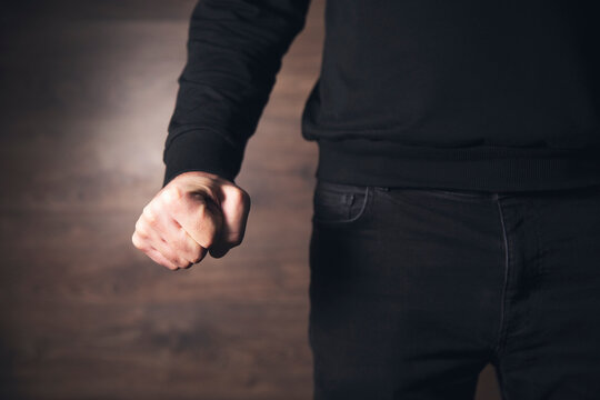 angry man fist on black wall background - Powered by Adobe