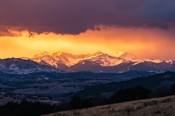 Obraz premium Mountains stretch across the horizon, bathed in an otherworldly golden light, symbolizing serenity and the eternal beauty of natural landscapes captured at dusk.
