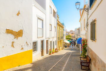 A picturesque hillside street with sidewalk cafes and shops in the whitewashed seaside town of Lagos, on the Algarve coast of Portugal.	
