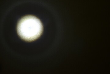 On a black background there is a bright round light with a soft reflection