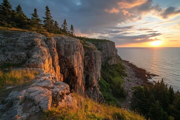 Fototapeta premium This image portrays a dramatic cliff landscape with lush trees atop, silhouetted by a vibrant sunset sky, highlighting the striking contrasts and natural beauty.