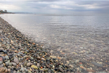 the sea wave rolls over the colorful pebbles on the Black Sea coast