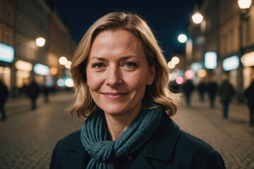 Close portrait of a smiling 40s Finnish woman looking at the camera, Finnish city outdoors at night blurred background