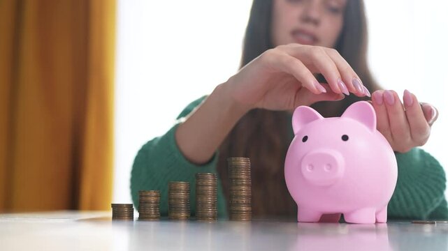 The girl smiles and puts coins in a piggy bank. Business family finance concept. A girl is saving money with her piggy bank. lifestyle A girl is saving money with coins in a bank.