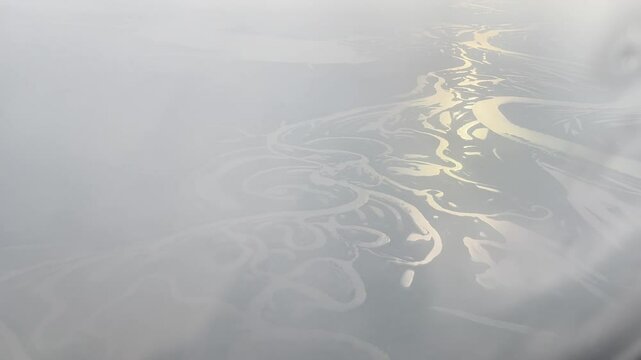 Blurred view of earth surface with river from frozen porthole of plane above