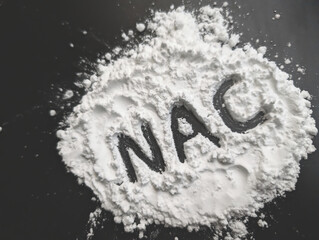 White powder on a black background. Letters NAC. Vitamines and bio hacking concept. Copy space