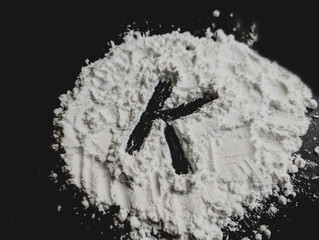 White powder on a black background. Letters K. Vitamin K. Bio hacking concept. Copy space