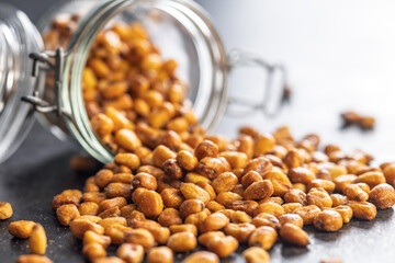 Roasted salted corn snack in jar on black table.
