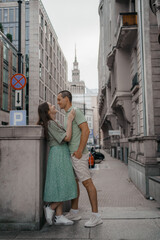 Happy couple of tourists walking embraced while sightseeing the town. Happy couple in front of palace of culture and science in Warsaw, Poland. Close up of a couple kissing.