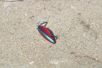 red metallic fishing lure on sidewalk