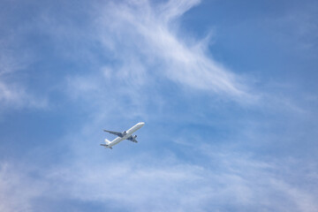  A striking view of a commercial airplane soaring through a vibrant blue sky with delicate, wispy clouds. This image represents the beauty of aviation and the limitless possibilities of global travel 