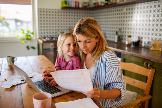 Mom working on bills with daughter at kitchen table