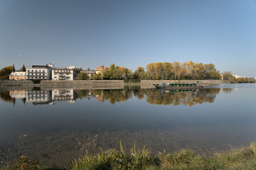 Riverside scene with a bridge, town buildings, and green riverbank.