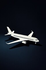 A minimalist paper model of an airplane casts striking shadows against a dark background.