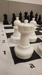 A close-up of a giant outdoor chess set featuring white pieces including the king, queen, bishops, knights, and rooks