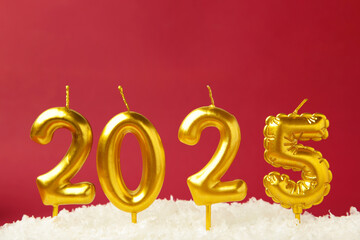 Holiday background Happy New Year 2025. Numbers of year 2025 made by gold candles on red background with snow.