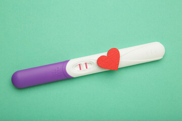 The pregnancy test with hearts on mint background. Health care concept. Top view