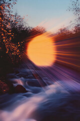 Fototapeta premium Sunset Over Flowing Water with Light Trails in Motion