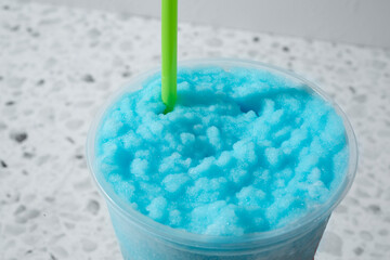 A view of a blue raspberry convenient store slushie in a plastic cup.
