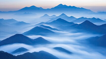 Misty blue mountains at sunrise, serene landscape.