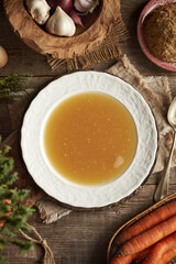 Chicken bone broth in white plate on a wooden table