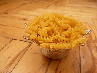 A delicate silver bowl filled with spiral pasta, merging culinary simplicity with ornate elegance,...