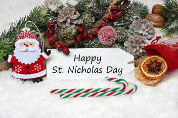 Happy St. Nicholas Day: Decoration with Santa Claus and candy cane in the snow.