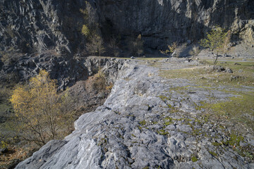 View of a quarry with steep rock walls and a grassy ledge in the foreground.