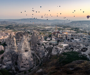 panorama sulle tipiche formazioni rocciose della cappadocia con le mongolfiere che le attraversano all'alba